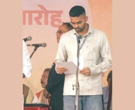 A man reading from a document while taking oath at a swearing-in ceremony on stage