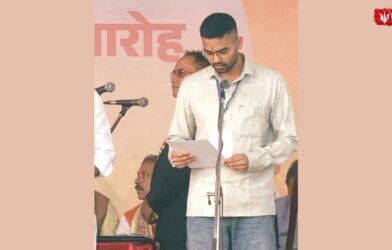A man reading from a document while taking oath at a swearing-in ceremony on stage