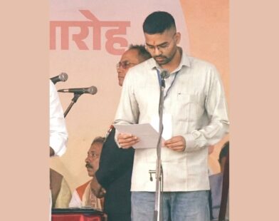A man reading from a document while taking oath at a swearing-in ceremony on stage