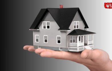 A hand holding a small house model with a bank loan approval symbol, representing financial support for home reconstruction