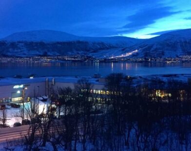 A snowy polar region where the sun does not rise for six months, showing a dark horizon and glowing sky at the edge of the world\