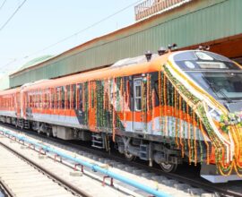 Vande Bharat sleeper train standing at the railway station with passengers and staff near the platform