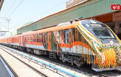 Vande Bharat sleeper train standing at the railway station with passengers and staff near the platform