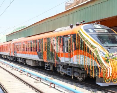 Vande Bharat sleeper train standing at the railway station with passengers and staff near the platform