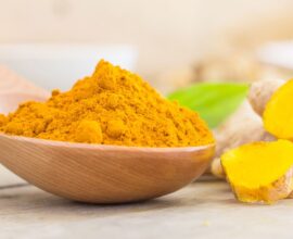 A bowl of turmeric powder with fresh turmeric roots placed beside it, highlighting the risks of excess turmeric consumption for kidney and liver health