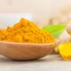 A bowl of turmeric powder with fresh turmeric roots placed beside it, highlighting the risks of excess turmeric consumption for kidney and liver health